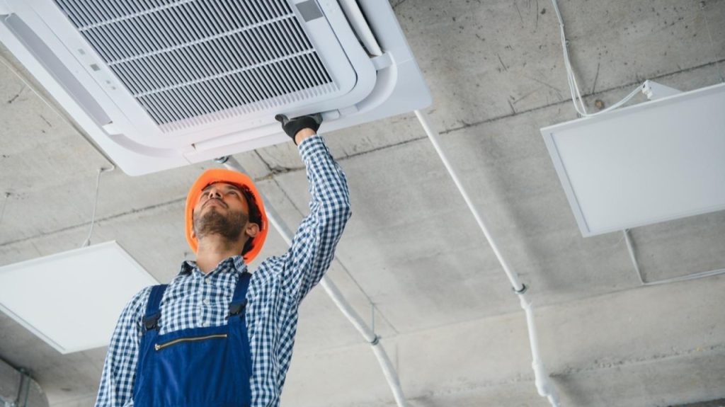 Técnico instalando una unidad HVAC tipo casete en el techo de un edificio
